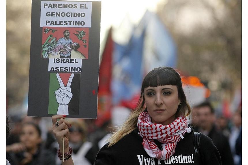 A pro-Palestinian demonstrator holds up a sign, which reads: "Stop the Palestinian genocide; Israel assassin", during a protest against Israel's military action in Gaza, in front of the Israeli embassy in Buenos Aires on July 16, 2014. -- PHOTO: REUT