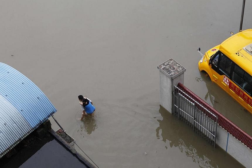 This picture taken on July 16, 2014 shows a man carrying a woman as he makes his way through a flooded area in Miluo, in central China's Hunan province.&nbsp;At least 20 people have died in the past week as torrential rain batters swathes of China, w