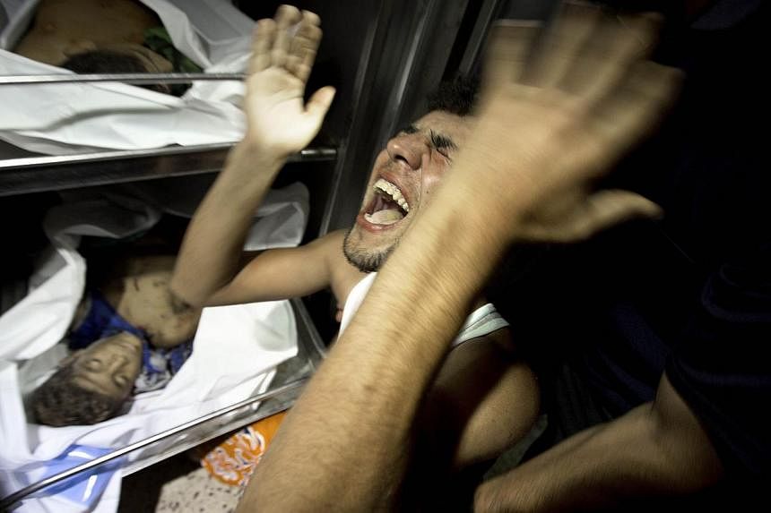 A relatives of four Palestinian boys, all from the Bakr family, mourns over the body of one of the boys at the morgue of al-Shifa hospital in Gaza City, on July 16, 2014. -- PHOTO: AFP