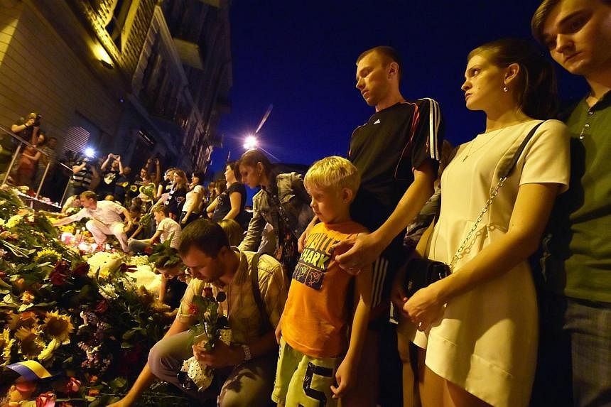 People light candles and place flowers in front of the Embassy of the Netherlands in Kiev on July 17, 2014, to commemorate passengers of Malaysian Airlines flight MH17 carrying 295 people from Amsterdam to Kuala Lumpur which crashed in eastern Ukrain