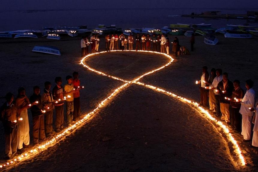 A 2009 file picture shows Indian villagers holding oil lamps as they surround a huge AIDS symbol on the beach at Nalsarovar, some 60km from Ahmedabad, on the eve of World Aids Day. Many of the passengers who died when a Malaysia Airlines plane crashe