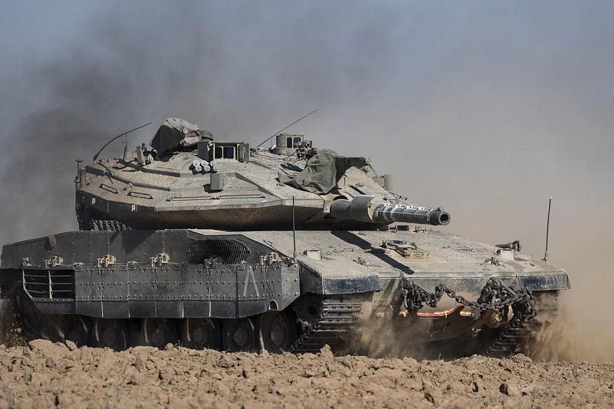 An Israeli Merkava tank rolls near Israel's border with the Gaza Strip on July 17, 2014. Israeli tank fire killed five people in the Gaza Strip, including a five-month-old baby, early on Friday, medics said. -- PHOTO: AFP
