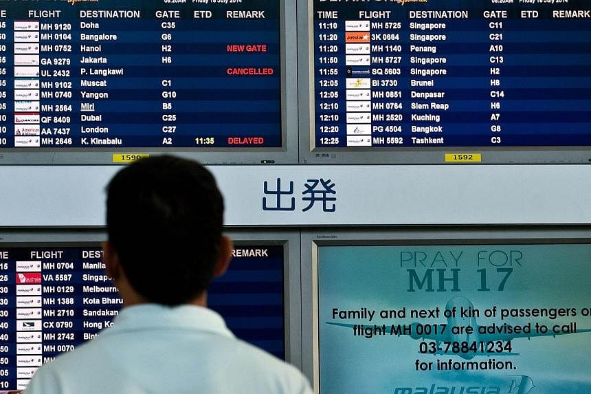 A Malaysian man looks at flight information screens displaying a solidarity message for Malaysia Airlines flight MH17 at Kuala Lumpur International Airport in Sepang on July 18, 2014. Malaysia Airlines System Bhd (MAS) shares fell sharply on Friday o