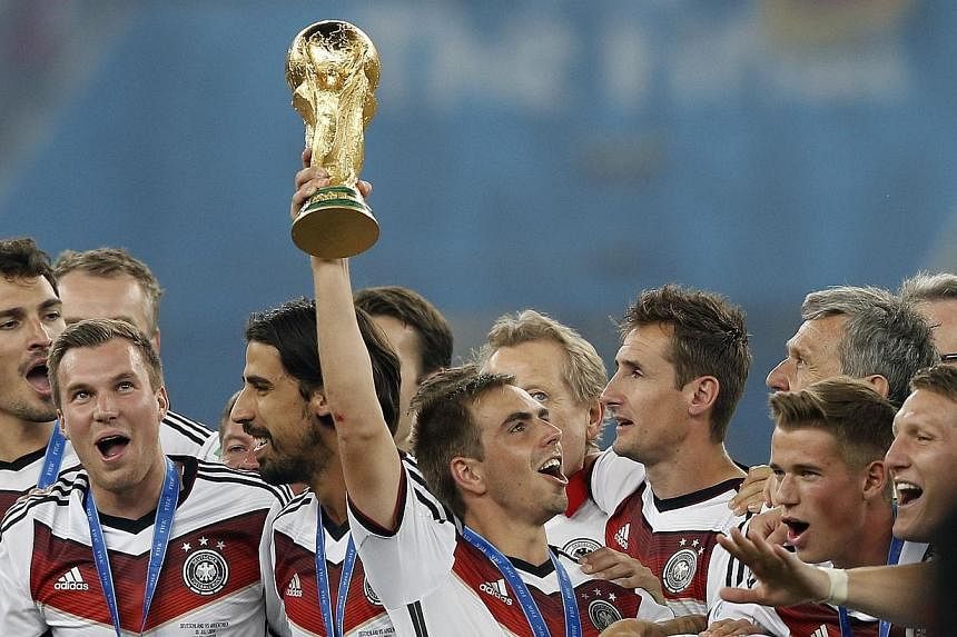 Germany's defender and captain Philipp Lahm (centre) holds The World Cup as he poses with teammates after his team's victory in the final football match between Germany and Argentina for the FIFA World Cup at The Maracana Stadium in Rio de Janeiro on