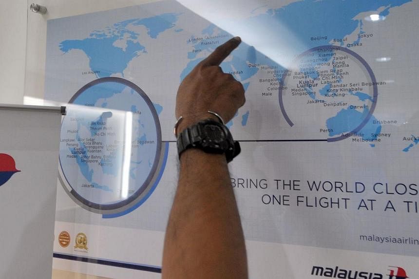 A man points at a world map at a Malaysia Airlines branch office in Jakarta on July 18, 2014 after Malaysia Airlines flight MH17 was shot down over Ukraine. -- PHOTO: AFP
