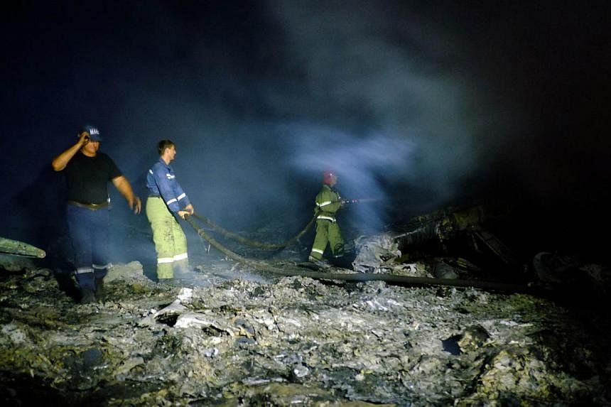 Firefighters spray water to extinguish a fire, on July 17, 2014 amongst the wreckages of the malaysian airliner carrying 298 people from Amsterdam to Kuala Lumpur after it crashed, near the town of Shaktarsk, in rebel-held east Ukraine. -- PHOTO: AFP