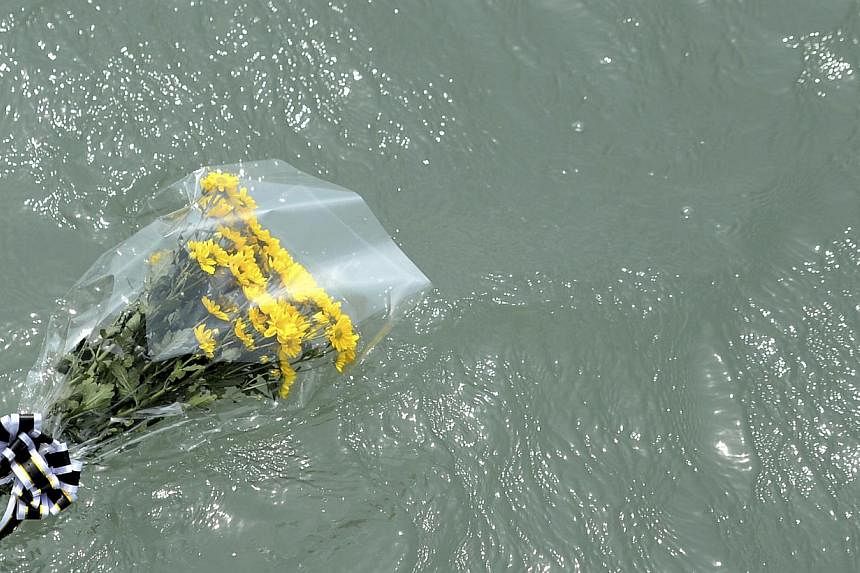 Flowers dedicated by family members to missing and dead passengers of sunken passenger ship Sewol float on the sea in Jindo on May 2, 2014. A culture of cosy personal ties that can blur the lines between businesses and those regulating them, of profi