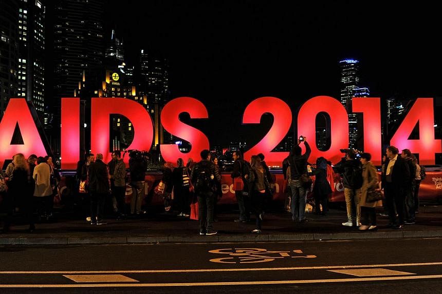 People gather next to a sign reading AIDS 2014 in Melbourne on July 18, 2014.&nbsp;Glen Thomas, a World Health Organisation (WHO) spokesman heading to the20th International AIDS Conference in Melbourne, was among the 298 people killed in the crash in