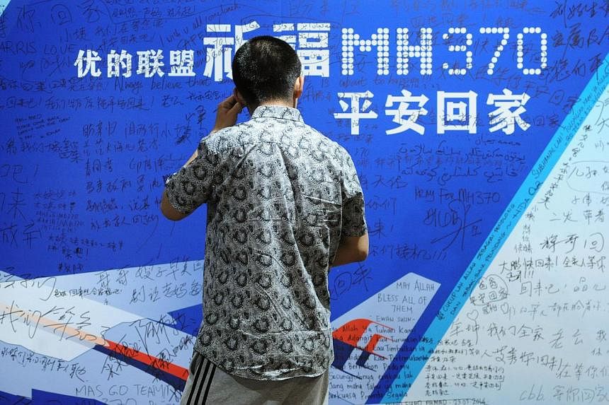 This file photo taken on March 30, 2014 shows a man looking at a billboard in support of missing Malaysia Airlines flight MH370 while relatives attend a meeting with delegates from Malaysia at a hotel in Beijing.&nbsp;Relatives of missing MH370 passe