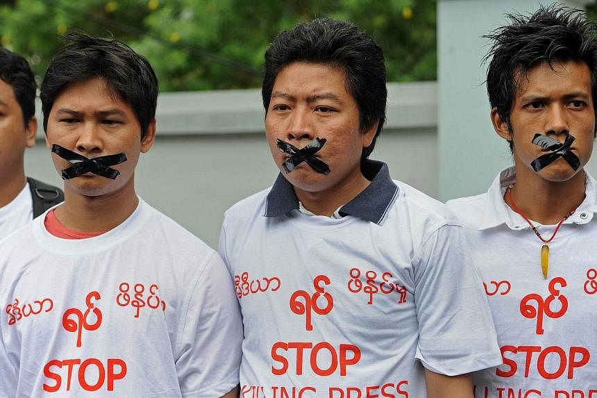 Myanmar journalists wearing T-shirts that say "Stop Killing Press" stage a silent protest for five journalists who were jailed for 10 years on July 10, near the Myanmar Peace Center on July 12, 2014. -- PHOTO: AFP