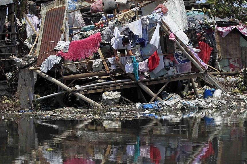 A woman hangs newly laundered clothes at a damaged house after Typhoon Rammasun (locally named Glenda) battered the town for two days, in Rosario, Cavite city, south of Manila July 18, 2014. -- PHOTO: REUTERS
