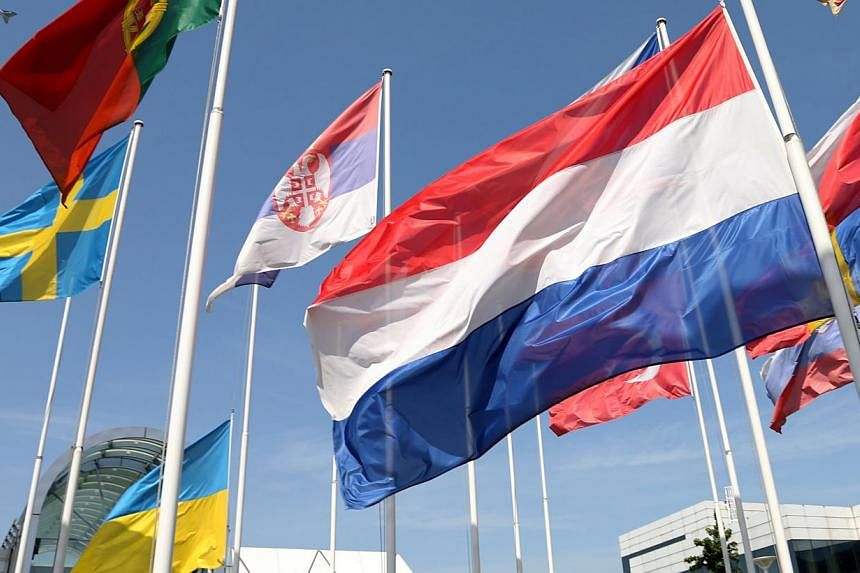 Dutch (right) and Ukrainian national flags are seen flying at half-mast outside the headquarters of Eurocontrol, Europe's air traffic regulator, in Brussels on July 18, 2014. -- PHOTO: REUTERS
