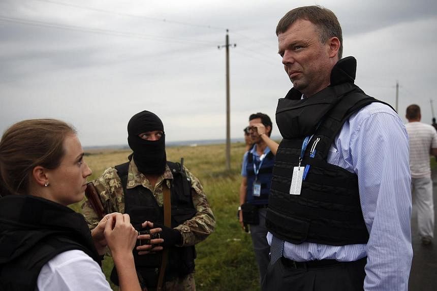 Organisation for Security and Cooperation in Europe (OSCE) monitors speak with a pro-Russian separatist at the crash site of Malaysia Airlines flight MH17, near the settlement of Grabovo in the Donetsk region, July 18, 2014. OSCE monitors were not ab