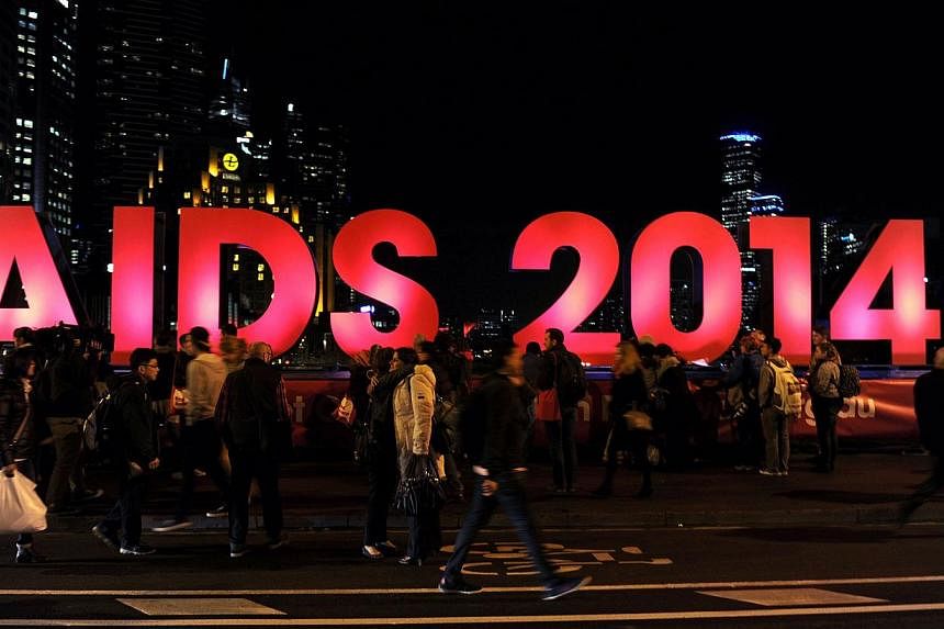 People gather next to a sign reading AIDS 2014 in Melbourne on July 18, 2014 after news that downed Malaysia Airlines flight MH17 was carrying many participants headed to the 20th International AIDS Conference planned this weekend in the Australian c