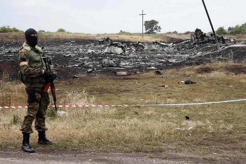 A pro-Russian separatist stands near a body at the crash site of Malaysia Airlines Flight MH17, near the settlement of Grabovo in the Donetsk region on July 19, 2014.&nbsp;The stench of death is now becoming almost unbearable over the wreckage of the