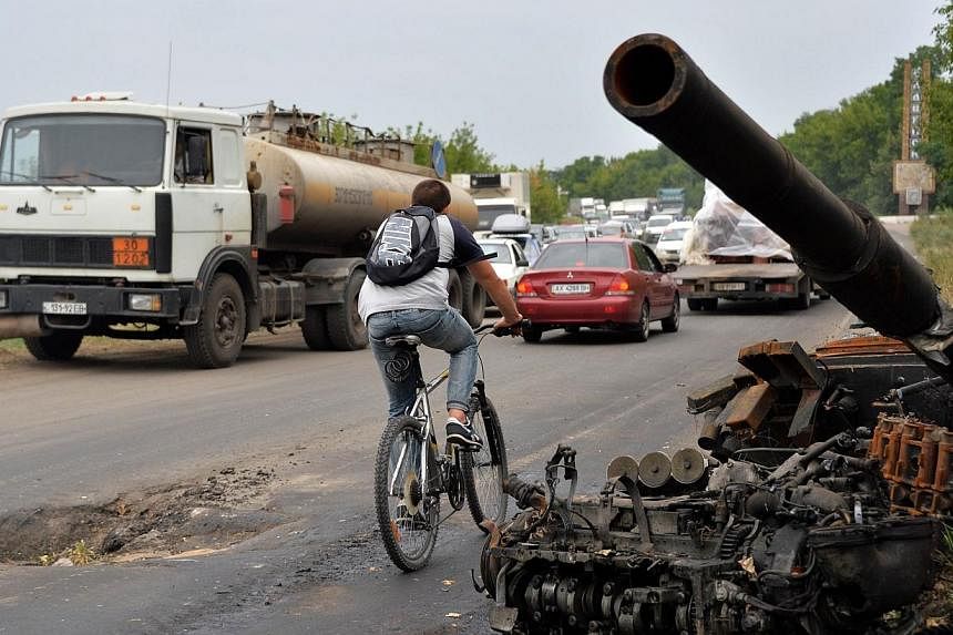 A man rides a bicycle past wrecked tanks and armored personnel carriers (APCs) left by pro-Russia militants on a road near the eastern Ukrainian city of Slavyansk on July 18, 2014.&nbsp;Ukraine has "compelling evidence"that the crew which operated th