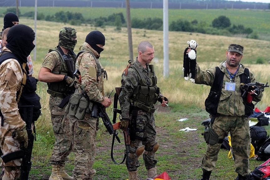 A pro-Russia militant holds up a stuffed animal as others look on at the site of the crash of a Malaysian airliner carrying 298 people from Amsterdam to Kuala Lumpur in Grabove, in rebel-held east Ukraine on July 18, 2014. Ukraine's government accuse