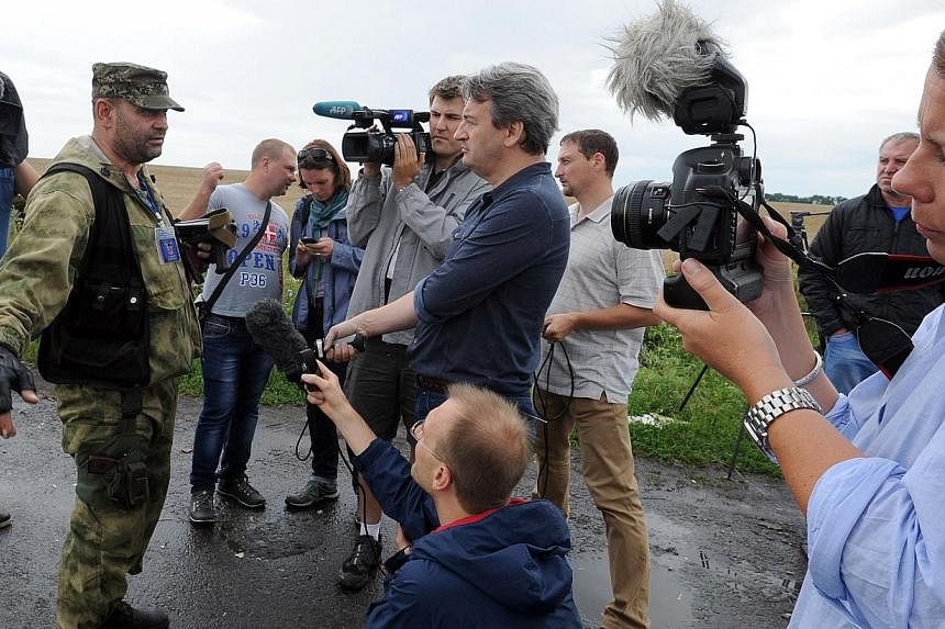 An armed pro-Russia militant attempts to stop journalists from accessing the site of the crash of a Malaysia Airlines plane carrying 298 people from Amsterdam to Kuala Lumpur in Grabove, in rebel-held east Ukraine on July 19, 2014. -- PHOTO: AFP