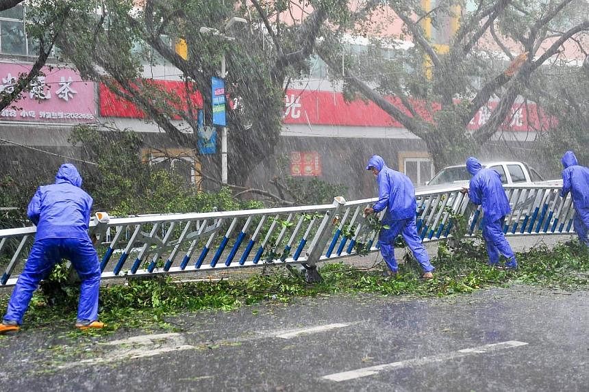 Maintanence workers put up a collapsed fence on a street as typhoon Rammasun brings torrential rains and strong wind to the area in Beihai, south China's Guangxi province on July 19, 2014. -- PHOTO: AFP