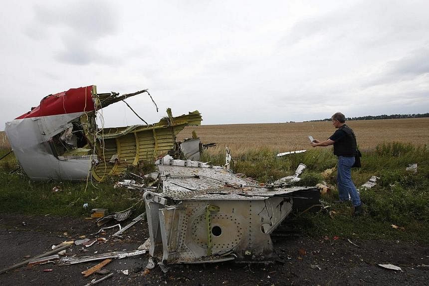 An Organisation for Security and Cooperation in Europe (OSCE) monitor takes a photograph at the crash site of Malaysia Airlines flight MH17, near the settlement of Grabovo in the Donetsk region on July 18, 2014.&nbsp;A Malaysian team, including two a