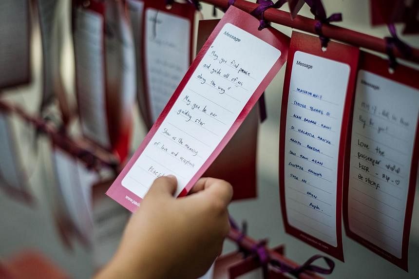 A visitor reads a prayer for passengers onboard Malaysia Airlines flight MH17 that crashed in eastern Ukraine, at a shopping mall in Kuala Lumpur on July 19, 2014. In a statement, the carrier said it will waive fees for passengers who wish to change 