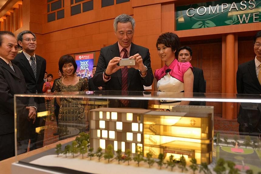 PM Lee (centre) takes a photo of the model of new Bukit Gombak Community Club as Ms Low Yen Ling, (second, right), Mayor of South West District, looks on. With them are (from left) Mr Joe Chan, PBM, Organising Chairman of Bukit Gombak Community Club 