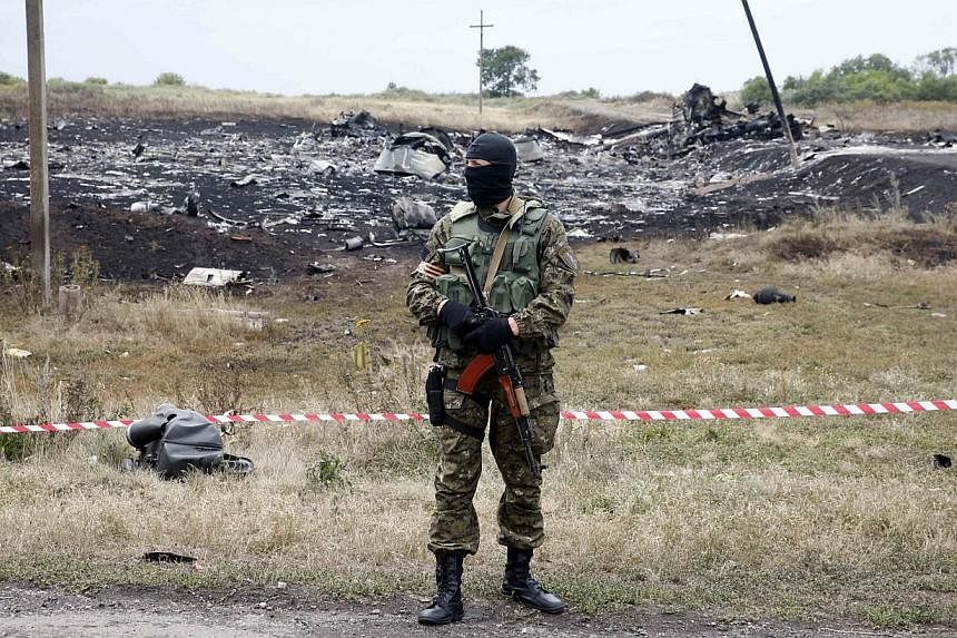 A pro-Russian separatist stands at the crash site of Malaysia Airlines Flight MH17, near the settlement of Grabovo in the Donetsk region July 19, 2014. -- PHOTO: REUTERS