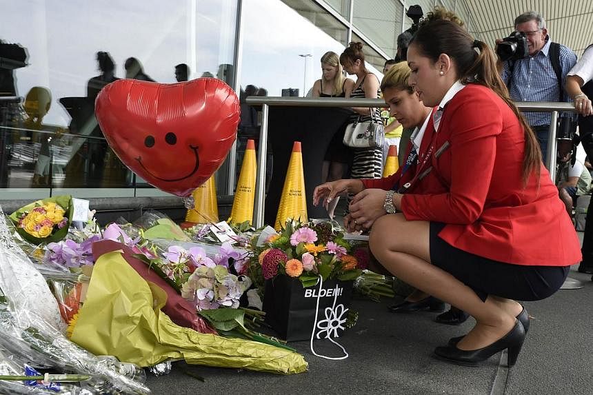Delta Airlines flight attendants place flowers in front of Schiphol airport on July 19, 2014, two days after Malaysia Airlines flight MH17 carrying 298 people from Amsterdam to Kuala Lumpur crashed in eastern Ukraine. -- PHOTO: AFP