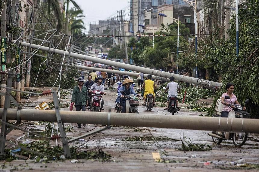 Residents travel on a street blocked by fallen electricity poles after Typhoon Rammasun hit Leizhou, Guangdong province on July 19, 2014.&nbsp;The death toll from the strongest storm to hit China in decades has reached 17, state media said on Sunday,