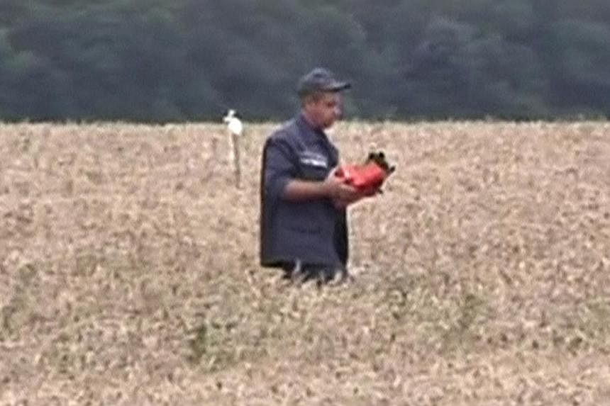 A rescue worker walks across a field carrying a flight data recorder at the crash site of Malaysia Airlines Flight MH17 in Hrabove July 18, 2014 in this still image taken from video.&nbsp;Pro-Russian rebels in eastern Ukraine said Sunday, July 20, 20