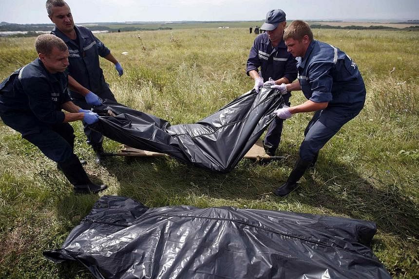 Members of the Ukrainian Emergency Ministry carry a body at the crash site of Malaysia Airlines Flight MH17, near the settlement of Grabovo in the Donetsk region on July 19, 2014.&nbsp;The local department of Ukraine's Emergencies Ministry in the eas