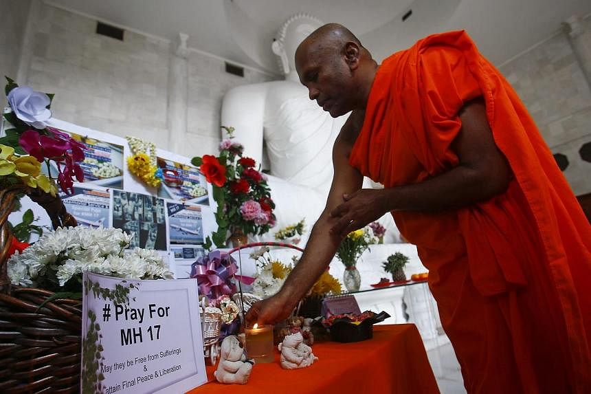 A monk performs a prayer during a special vigil for victims of the downed Malaysia Airlines Flight MH17, inside a Buddhist temple in Kuala Lumpur July 20, 2014. More than a hundred Buddhist devotees and members of the public turned up for a memorial 