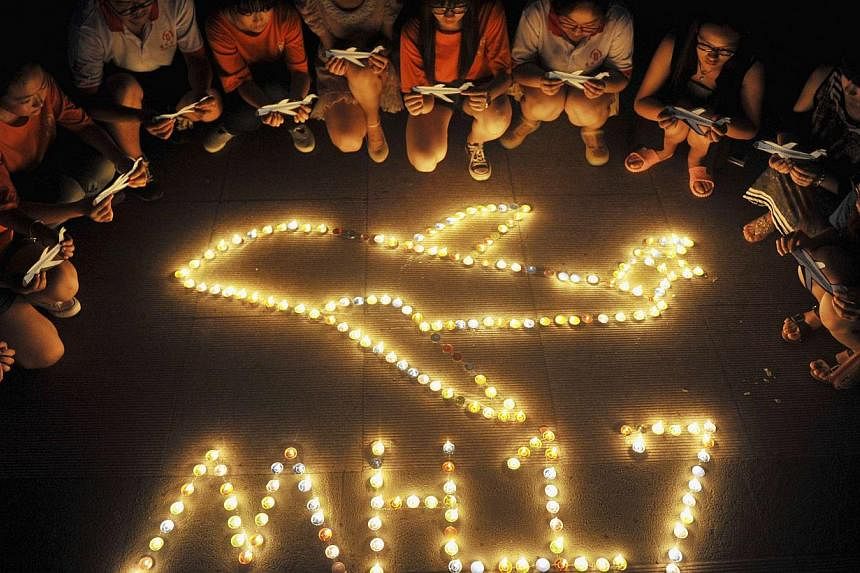 College students gather around candles forming the shape of an airplane, during a candlelight vigil for victims of the downed Malaysia Airlines Flight MH17, at a university in Yangzhou, Jiangsu province on July 19, 2014.&nbsp;Malaysia Airlines said o