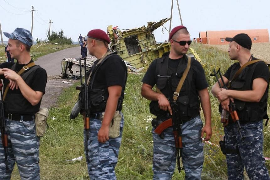 Armed pro-Russian separatists stand guard at a crash site of Malaysia Airlines Flight MH17, near the village of Hrabove, Donetsk region on Sunday, July 20, 2014.&nbsp;France, Britain and Germany warned Russia on Sunday it could face further EU sancti
