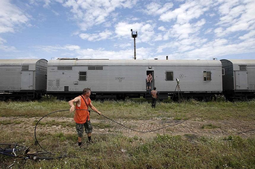 Railway employees are pictured as they work near refrigerator wagons, which according to employees and local residents contain bodies of passengers of the crashed Malaysia Airlines Boeing 777 plane, at a railway station in the town of Torez, Donetsk 