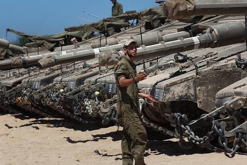 Israeli soldiers work on their Merkava tanks in an army deployment area near Israel's border with the Gaza Strip on July 11, 2014.&nbsp;Israel's army said Sunday it was expanding its ground offensive against the Gaza Strip, as the bloodiest conflict 