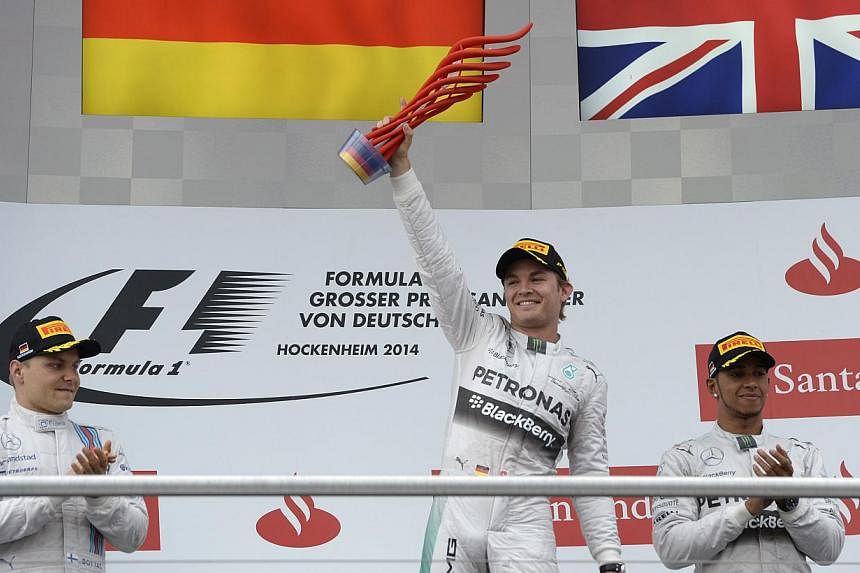 Mercedes-AMG's German driver and race winner Nico Rosberg (C) celebrates next to second placed Williams' Finnish driver Valtteri Bottas (L) and Mercedes-AMG's British driver Lewis Hamilton (R) after the German Formula One Grand Prix at the Hockenheim
