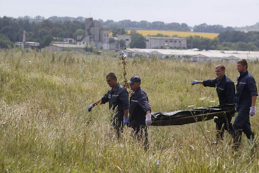 Members of the Ukrainian Emergency Ministry carry a body at the crash site of Malaysia Airlines Flight MH17, near the settlement of Grabovo in the Donetsk region on July 19, 2014. &nbsp;-- PHOTO: REUTERS
