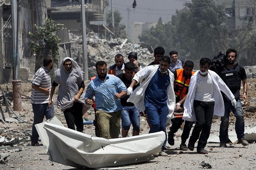 Medics evacuate a body from Gaza's eastern Shejaiya district on July 20, 2014. -- PHOTO: AFP