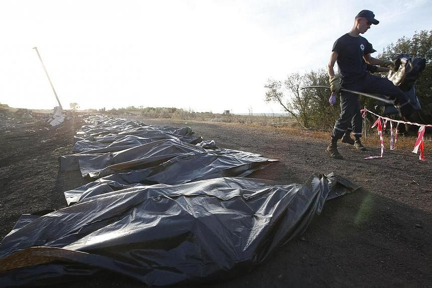 Members of the Ukrainian Emergencies Ministry walk past body bags at the crash site of Malaysia Airlines Flight MH17 near the village of Hrabove, Donetsk region, on July 20, 2014. -- PHOTO: REUTERS