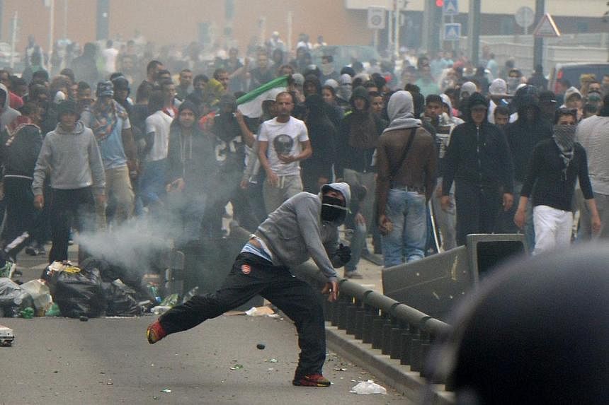 A rioters throws a projectile at French riot police officers in Sarcelles, a suburb north of Paris, on July 20, 2014, after clashes following a demonstration denouncing Israel's military campaign in Gaza and showing support to the Palestinian people.