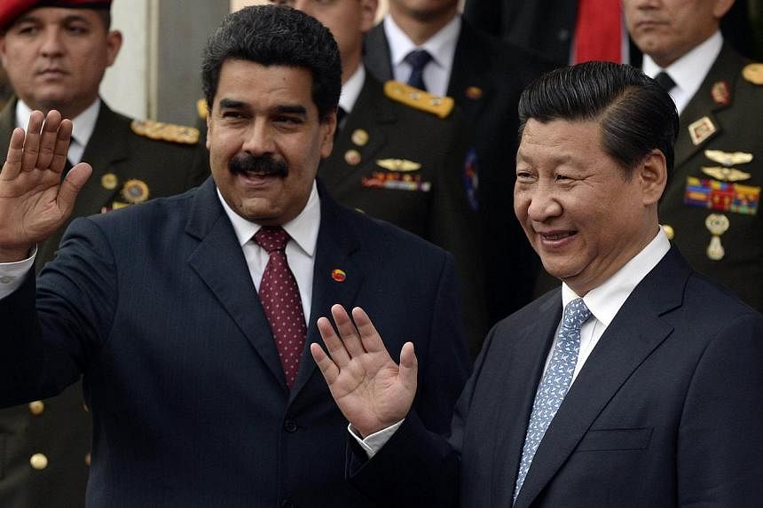 Venezuelan President Nicolas Maduro (left) and China's President Xi Jinping wave during a meeting in Miraflores Presidential Palace, in Caracas on July 20, 2014. -- PHOTO: AFP&nbsp;
