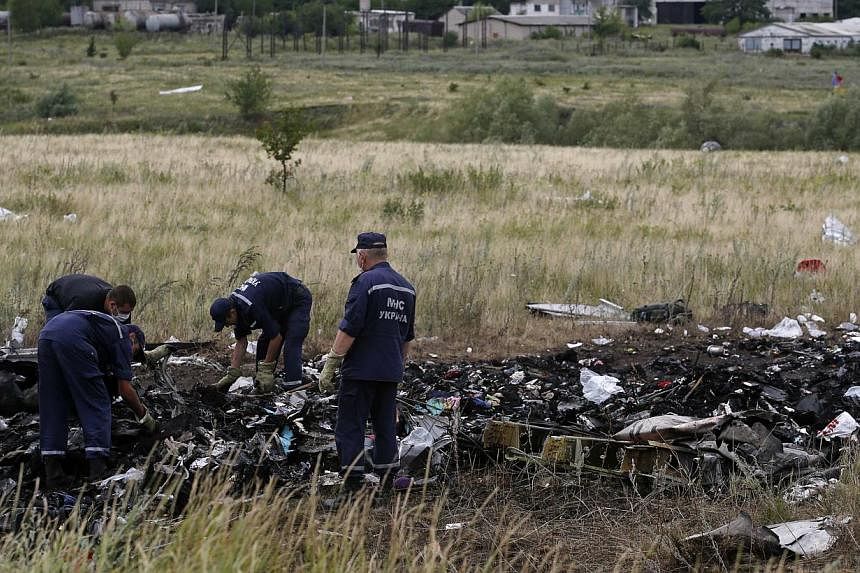 Members of the Ukrainian Emergencies Ministry work at a crash site of Malaysia Airlines Flight MH17, near the village of Hrabove, Donetsk region on July 20, 2014. -- PHOTO: REUTERS