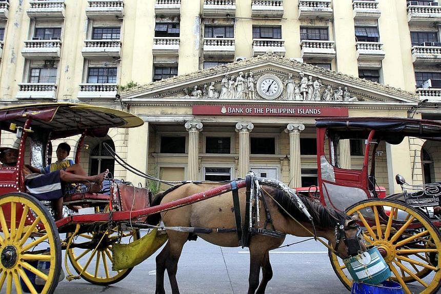 &nbsp;A horse cart is parked in front of the Bank of the Philippine Islands in Manila July 1, 2014.&nbsp;Philippine President Benigno Aquino has signed into law a bill allowing foreign banks to take full control of local lenders, in line with the gov