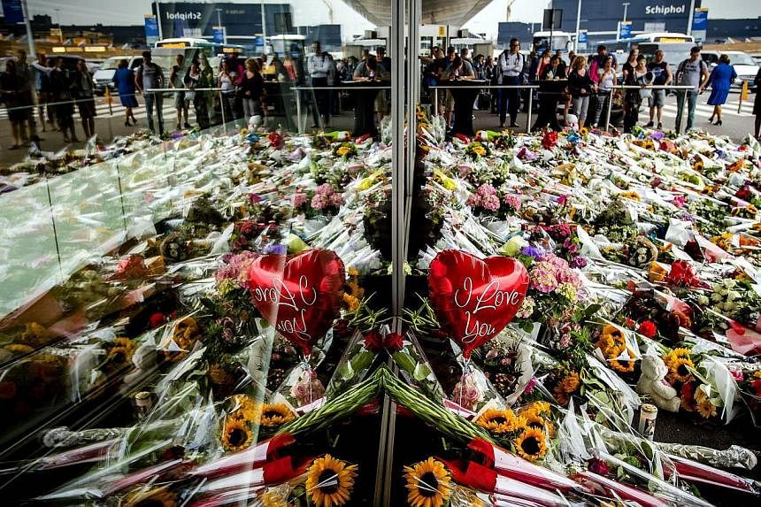 People look at the flowers left in remembrance for the victims of the MH17 plane crash at Schiphol Airport, near Amsterdam, on July 21.&nbsp;A bereaved Dutch father has written a savagely ironic open letter to whoever shot down flight MH17, "thanking