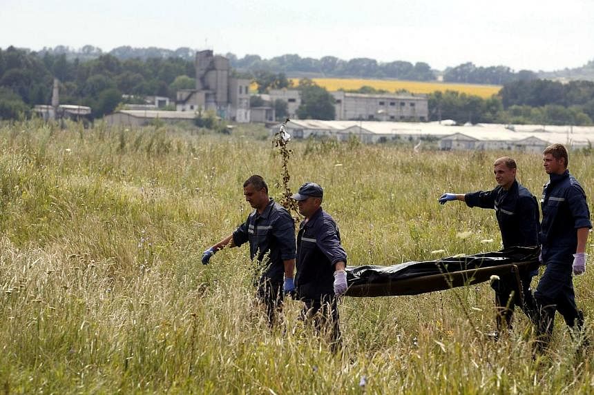 Members of the Ukrainian Emergency Ministry carry a body at the crash site of Malaysia Airlines Flight MH17, near the settlement of Grabovo in the Donetsk region on July 19, 2014.&nbsp;Ukraine is willing to hand over coordination of an investigation 