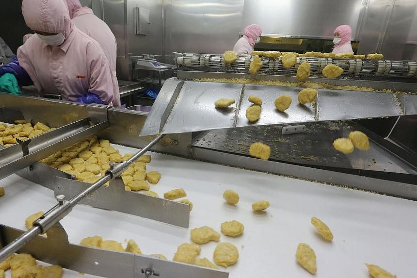 This picture taken on July 20, 2014, shows workers producing food at the Shanghai Husi Food Co., a factory of US food provider OSI Group, in Shanghai.&nbsp;Shanghai has shut a factory of OSI Group for selling out-of-date meat to restaurant giants inc