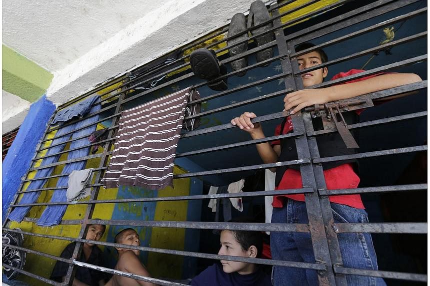 Youths look through a barred window inside a home known as "La Gran Familia" (The Big Family), in the western city of Zamora July 17, 2014. -- PHOTO: REUTERS