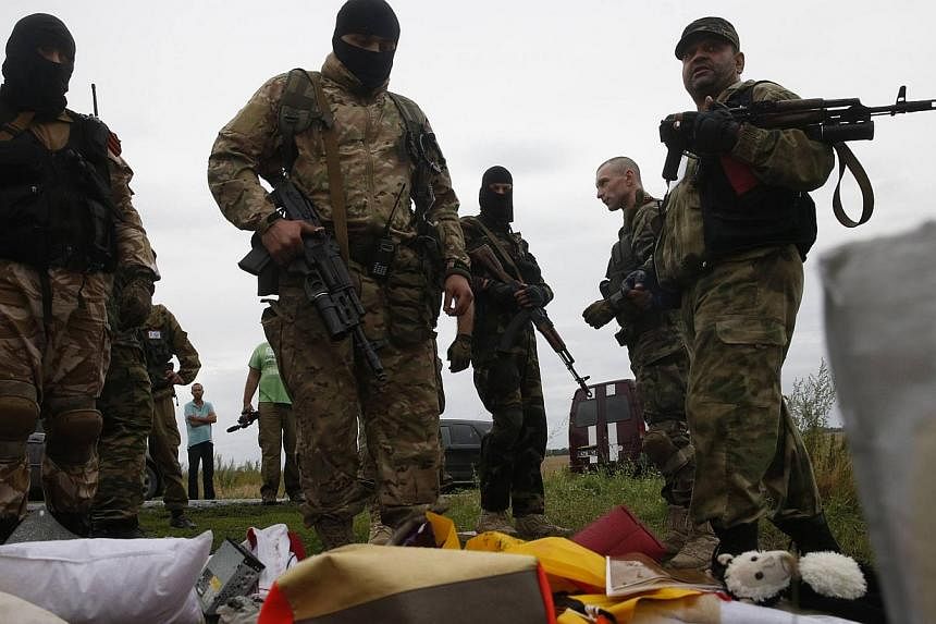 Pro-Russian separatists look at passengers' belongings at the crash site of Malaysia Airlines flight MH17, near the settlement of Grabovo in the Donetsk region on July 18, 2014. -- PHOTO: REUTERS