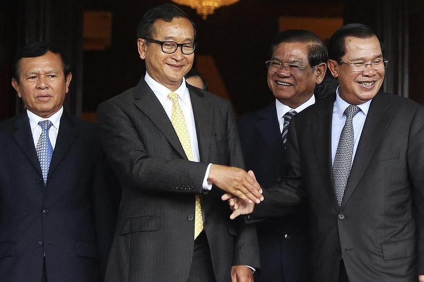 Cambodia's Prime Minister Hun Sen (second from right) shakes hands with Sam Rainsy (second from left), president of the Cambodia National Rescue Party (CNRP), after a meeting at the Senate in central Phnom Penh on July 22, 2014.&nbsp;-- PHOTO: REUTER